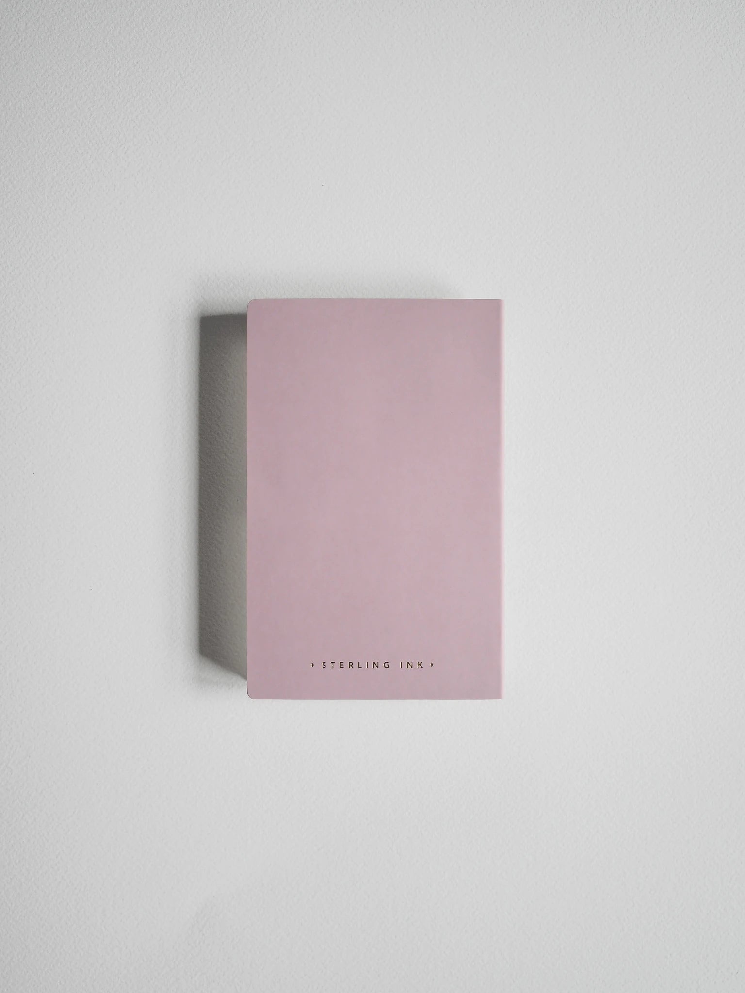 A minimalist pink notebook with 'STERLING INKY' printed in small black letters at the bottom, shown standing upright against a neutral light gray background.
#Color_Fairyfloss
