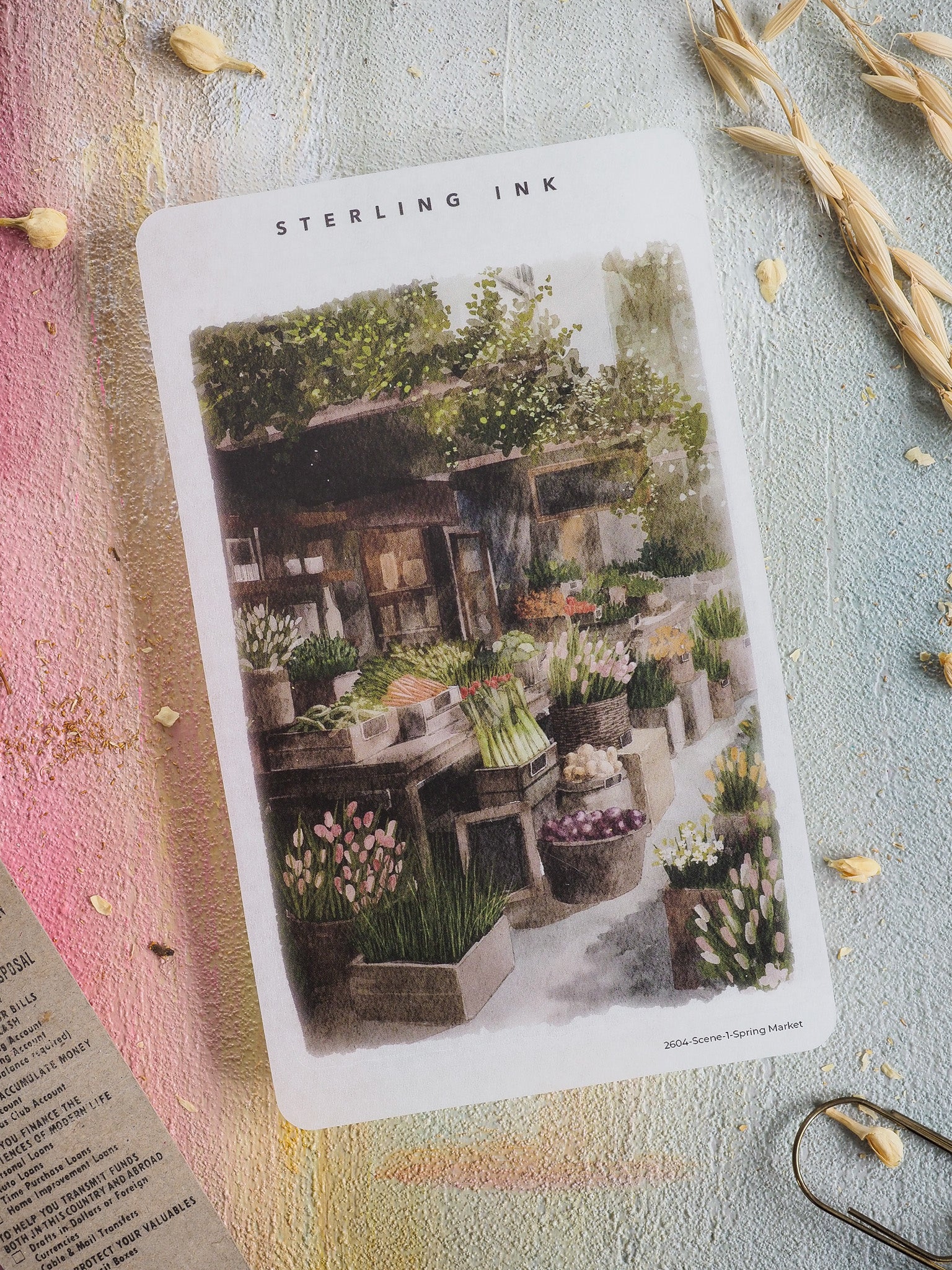 Watercolor illustration featuring a vibrant spring market scene with rustic wooden stalls, overflowing flower boxes, and fresh gardening supplies.