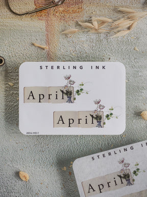 Elegant spring-themed sticker for April, featuring the month name and delicate watercolor floral illustrations with green botanical accents.