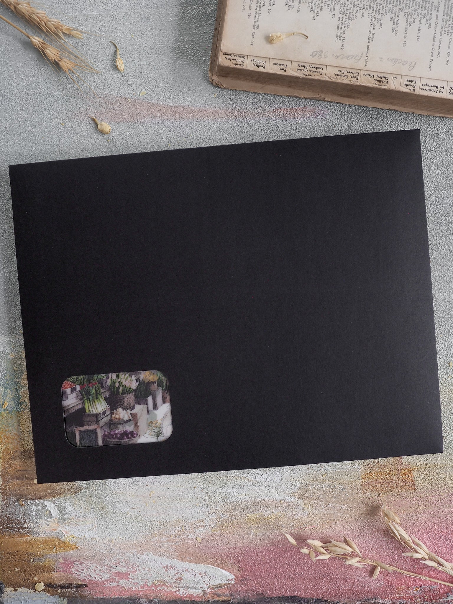 Matte black cardstock featuring a corner sticker of lush potted herbs and vibrant spring greenery, embodying the April floral theme.