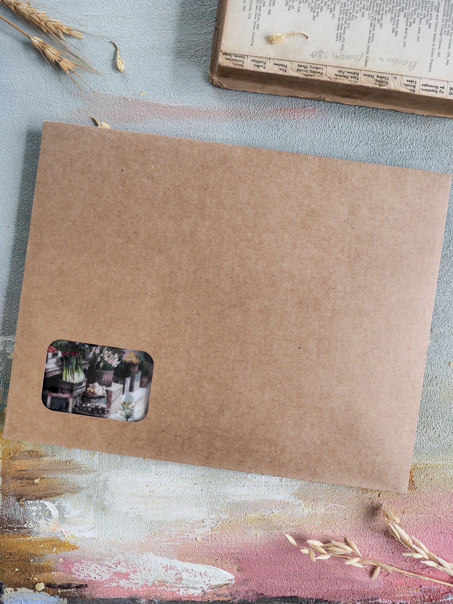 Natural brown kraft paper stationery featuring a small, decorative sticker with muted botanical illustrations, perfect for seasonal subscription kit organization.