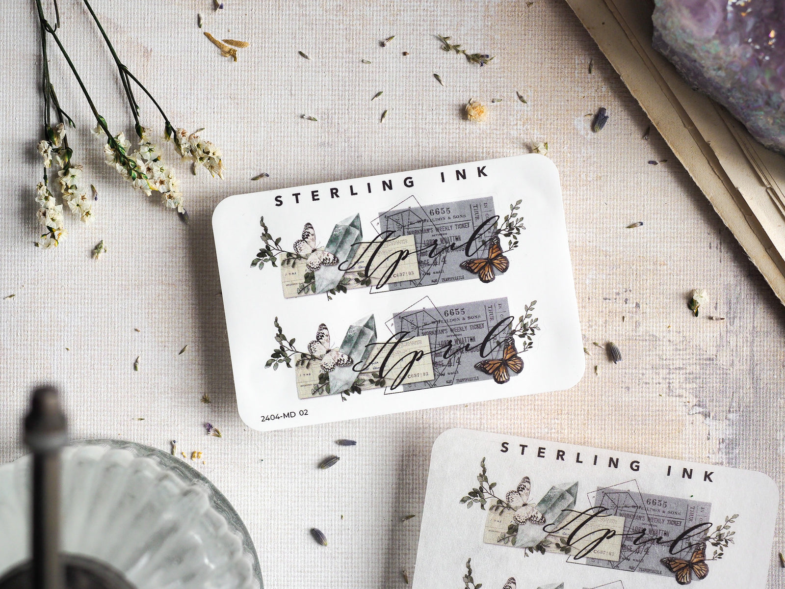 Vintage April 2024 sticker featuring a delicate botanical design with sketched houses, natural elements, and intricate butterfly motifs.