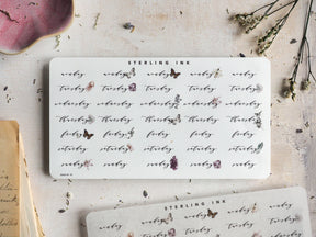 A set of aesthetic, white week day stickers featuring rustic typography and delicate, printed accents of florals and butterflies for journaling.