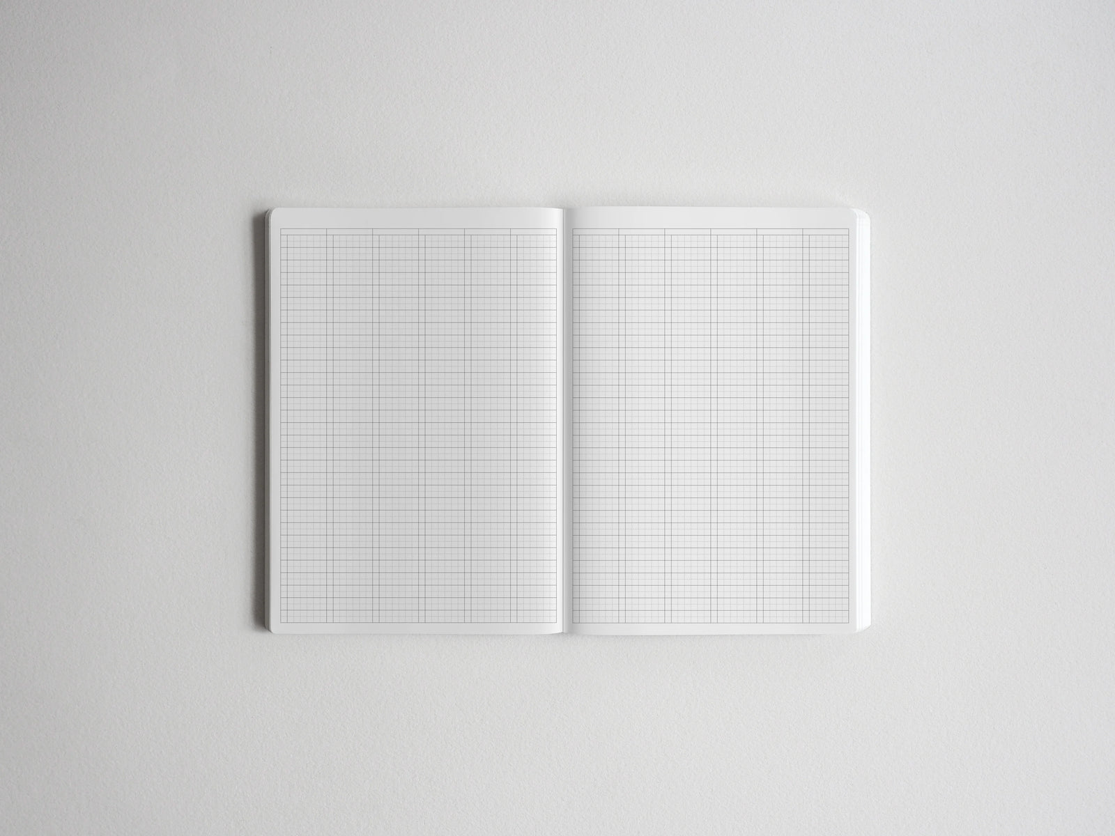 Open graph paper notebook showing two pages of crisp white, precisely gridded paper, perfect for structured drawing, technical drafting, or academic planning.