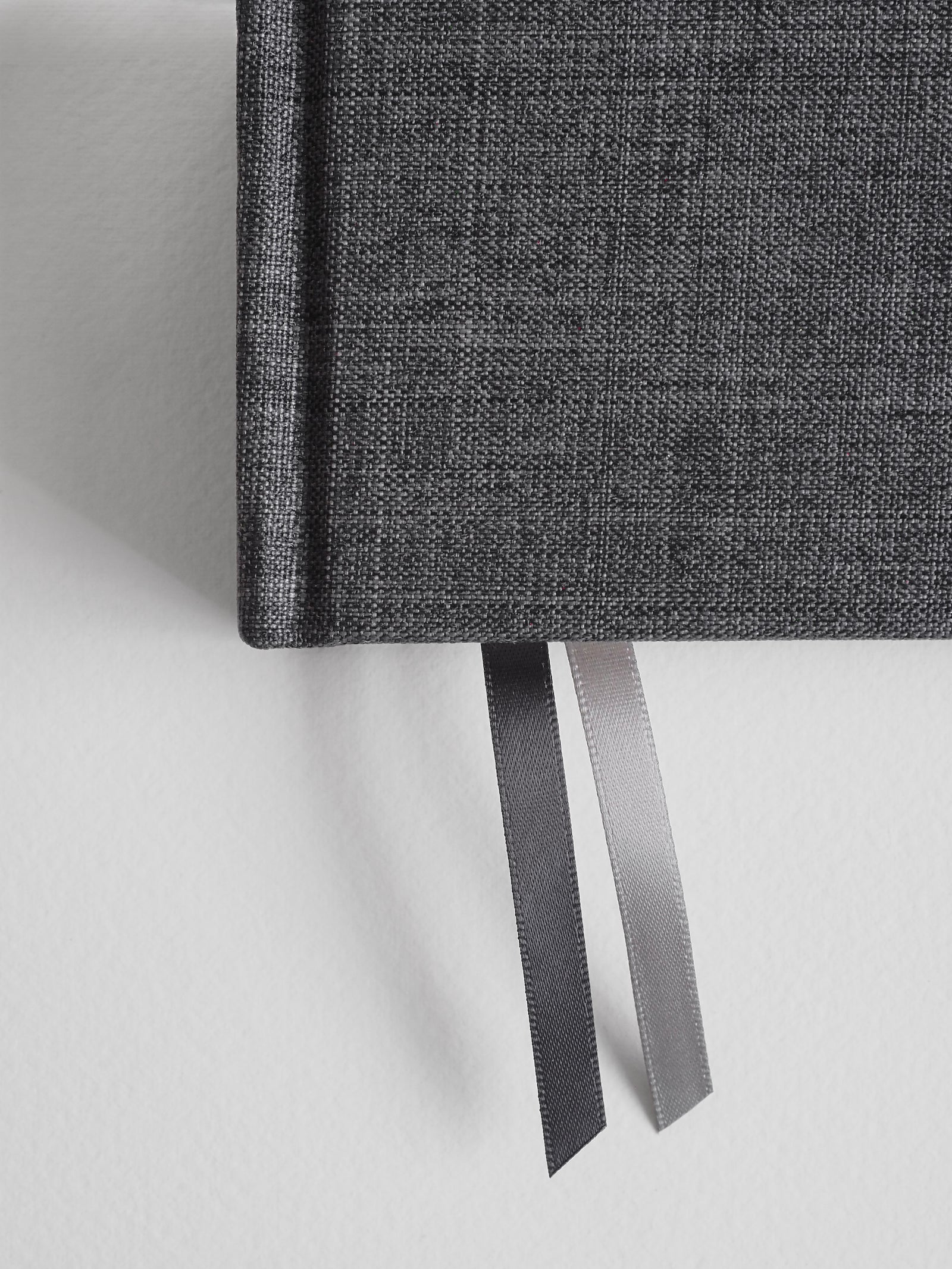 Durable B6 academic planner featuring a dark charcoal gray textured fabric cover, complemented by two contrasting satin ribbon bookmarks for comprehensive year organization.