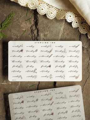 Delicate May 2025 calendar stickers featuring sweet, natural botanical illustrations of small sprigs, leaves, and blooms on light cardstock.