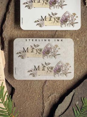 Charming May month sticker featuring rustic, vintage botanical illustrations of purple spring flowers and lettering, perfect for journaling or planners.