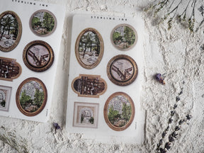 Sheet of assorted vintage picture frame stickers featuring distressed gold and brown borders surrounding antique architectural scenes like greenhouses and old city passages.