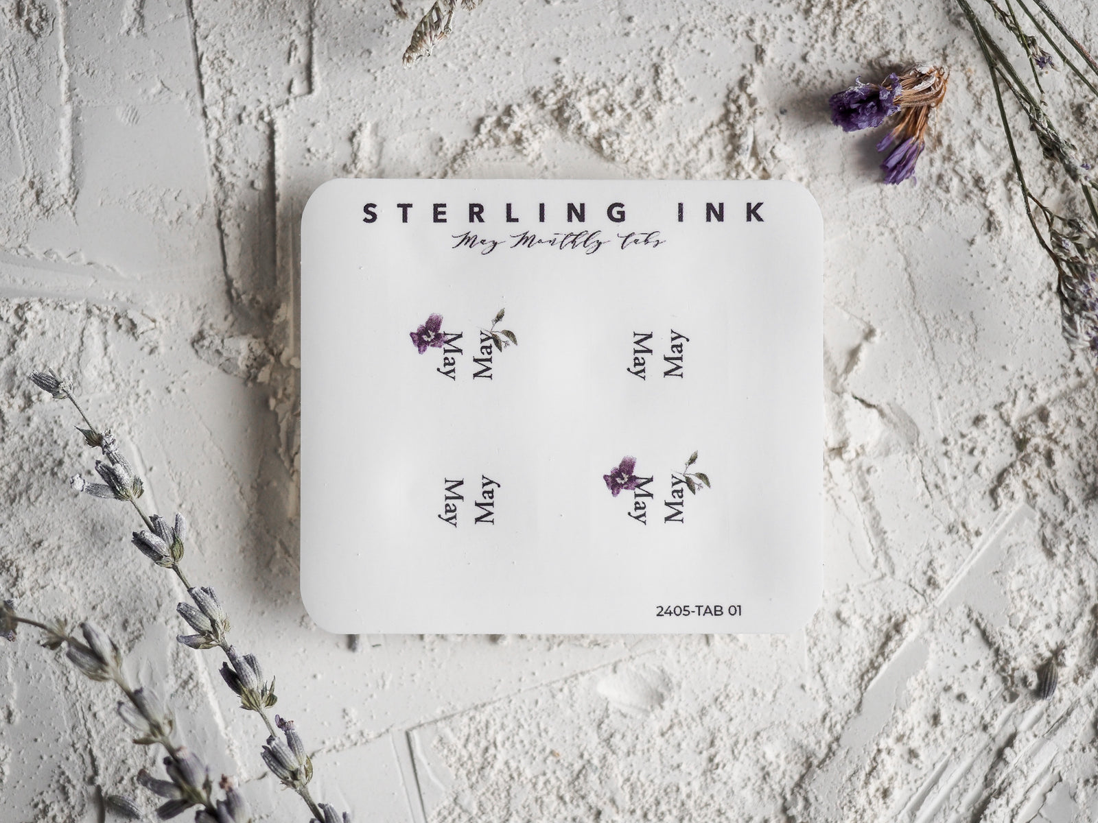 White monthly planner tabs featuring "May" printed six times, each accompanied by a delicate, purple lavender floral illustration on cream card stock.