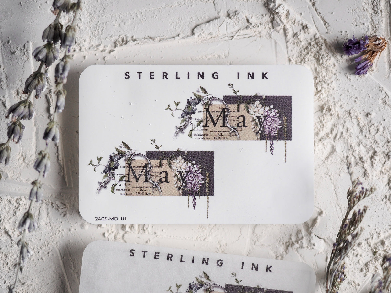 Elegant spring-themed sticker featuring the word "May" surrounded by delicate watercolor clusters of purple, green, and cream floral blooms.