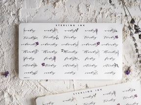 Decorative "STEARLING INK" calendar stickers marking the days of the week for May 2024, featuring script lettering and elegant daily labels.