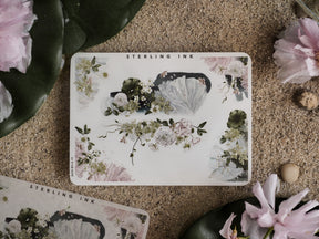 Delicate botanical sticker sheet featuring clustered designs of pale pink and white roses, leafy vines, and shimmering holographic floral accents for journaling.