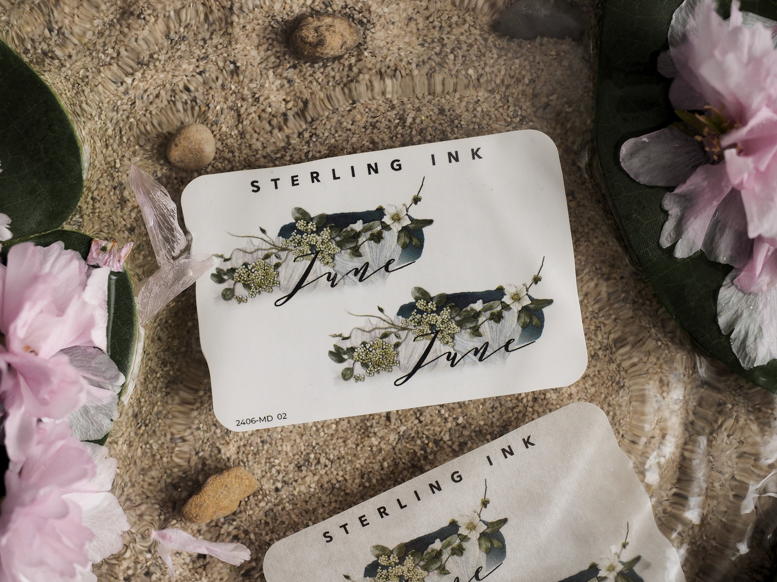 Elegant June month sticker featuring "STERLING INK" branding and lush botanical illustrations surrounding the calligraphy script in natural green and cream tones.
