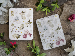 Two sticker sheets displaying various watercolor botanical illustrations of floral elements in muted dusty pink, pale blue, and sage green tones.