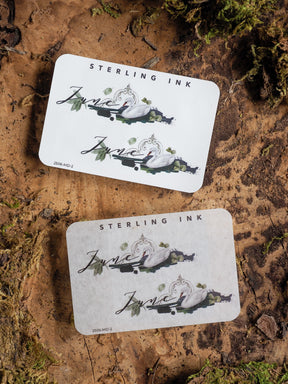 Elegant June 2025 month sticker featuring a delicate script and detailed illustration of swans amidst lush greenery.