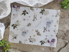 Elegant vellum print adorned with soft watercolor florals and scattered botanical sketches in shades of dusty purple, sage green, and cream.