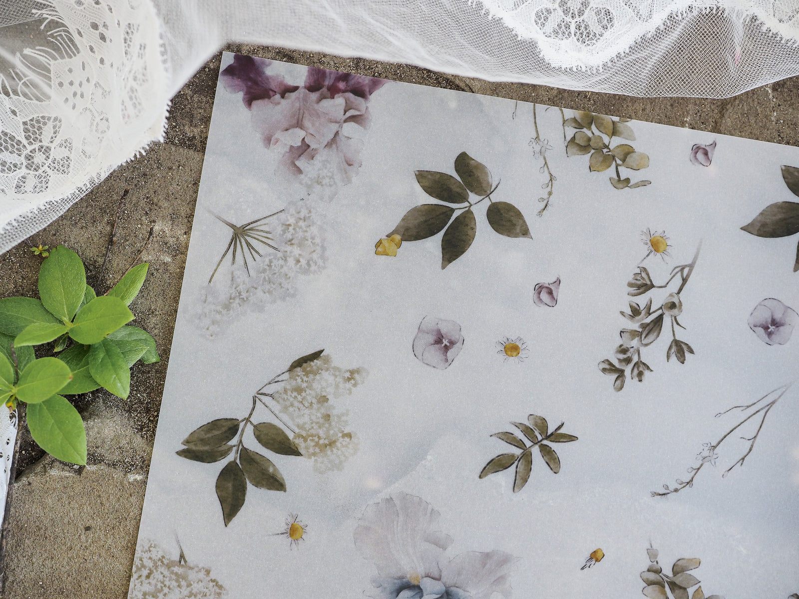 Watercolor botanical print featuring muted, elegant tones of soft purple, sage green, and gray, showcasing scattered leaves and gentle floral clusters.