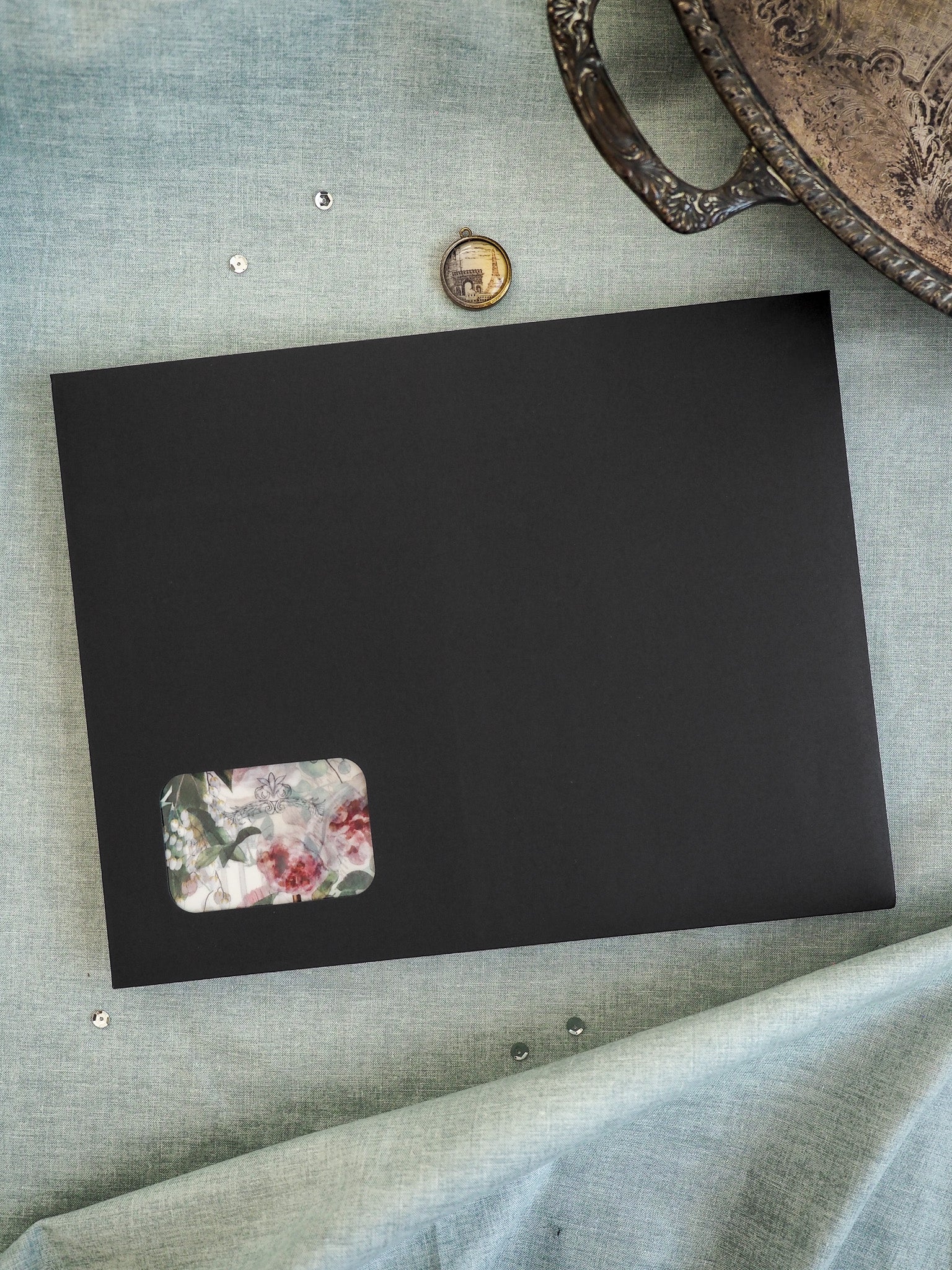 Minimalist black board displaying a delicate watercolor floral sticker with a vibrant botanical pattern in pink, red, and green tones.