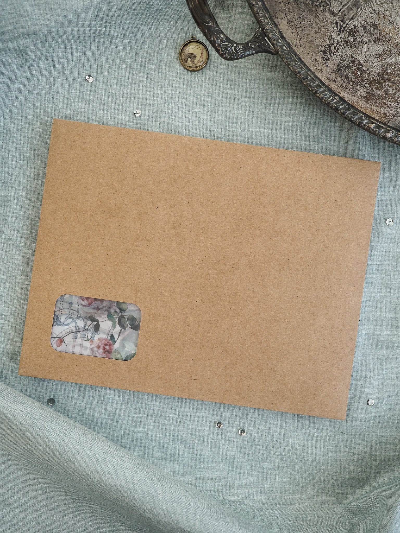 Brown kraft cardstock featuring a decorative sticker with a delicate pink and green floral botanical pattern.