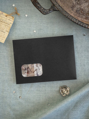 Black square card featuring a central, faded, vintage-style sticker illustration of an architectural sketch or building detail.