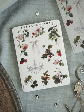 Watercolor botanical sticker featuring arrangements of pink roses, white flowers, green foliage, and deep red berries, accented by a delicate chandelier graphic.