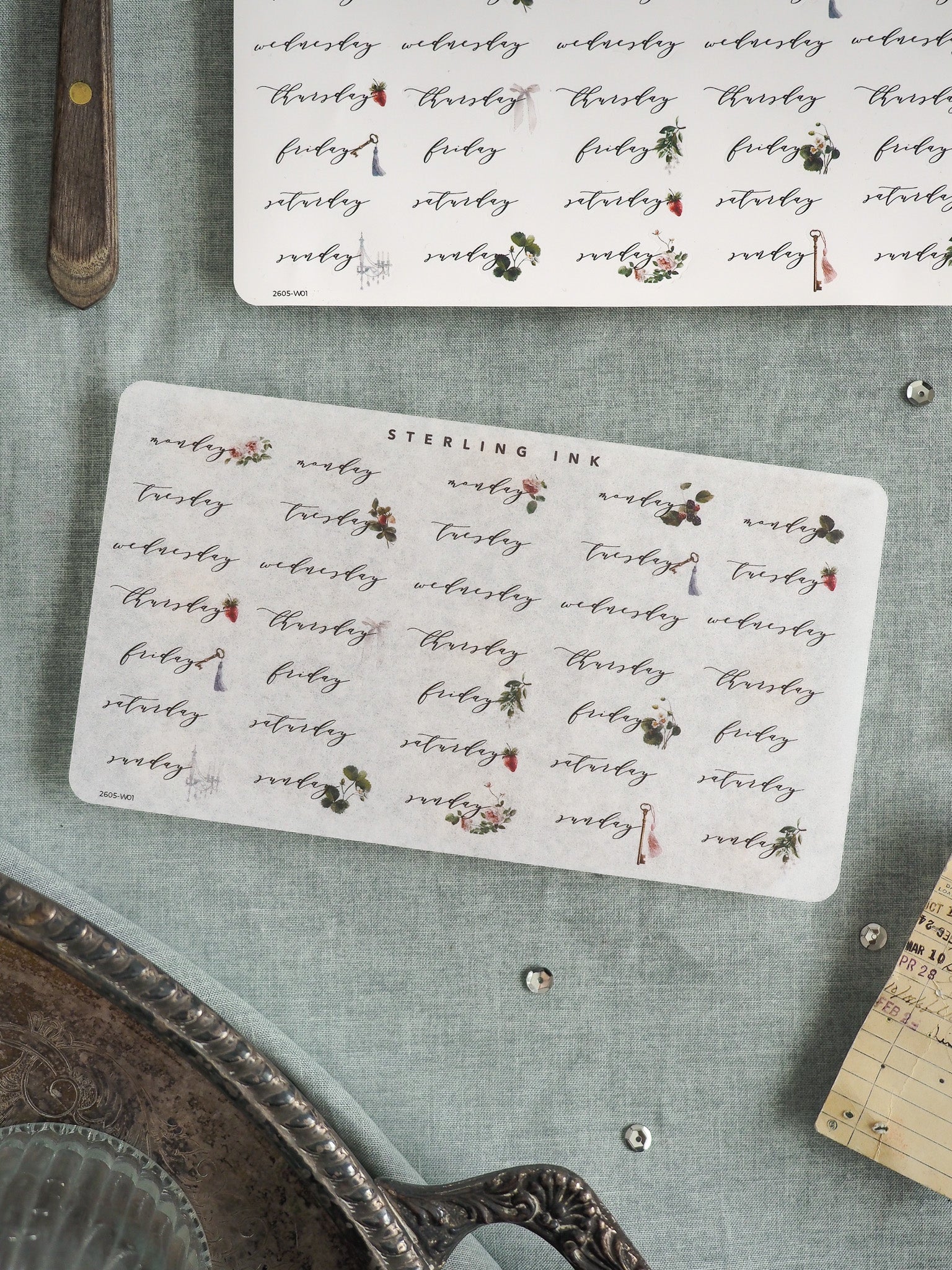 Decorative "Sterling Ink" label featuring repeating handwritten words and delicate red and green floral motifs, suitable for scrapbooking, journaling, or stationery decor.