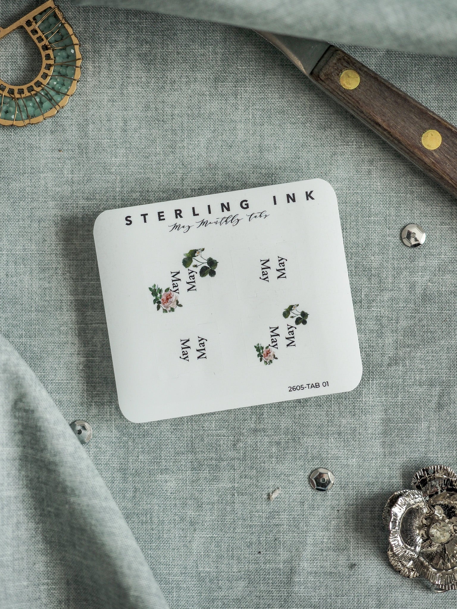 White "May Monthly Tabs" sticker featuring the text "STERLING INK" and a charming seasonal floral design pattern.
