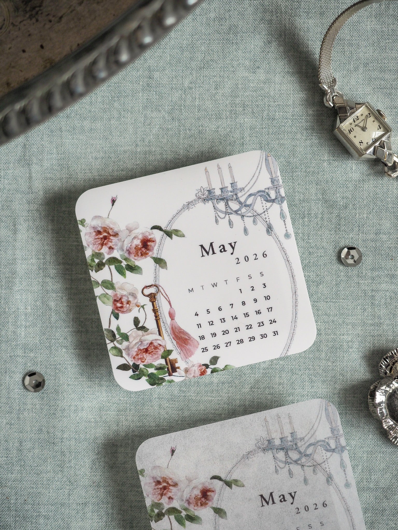 Elegant May 2026 calendar sticker featuring soft pink watercolor roses and delicate antique hanging accents, ideal for romantic planner decoration.