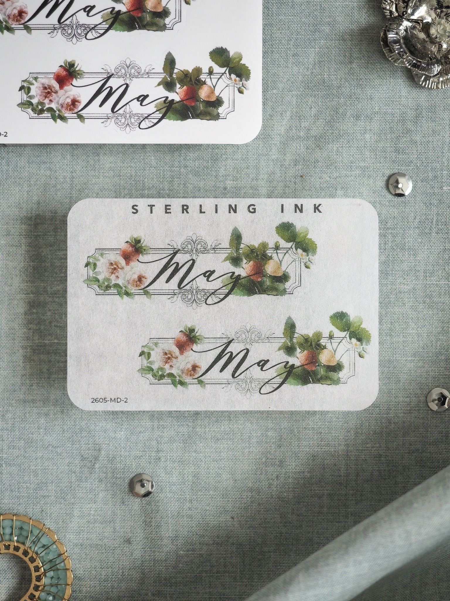 Elegant "May" decorative labels featuring watercolor floral wreaths in shades of blush and sage green, printed with cursive script and branded by Sterling Ink.