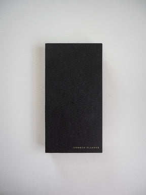 A compact, matte black planner featuring a textured, faux leather cover and minimalist "COMMON PLANNER" branding across the bottom.