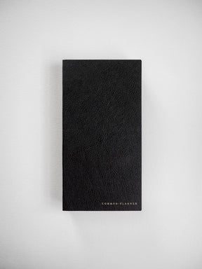A textured, solid black planner bound in faux leather, featuring the brand name "COMMON PLANNER" printed on the bottom.