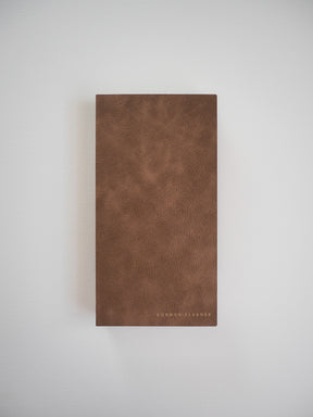 Rich brown, textured faux leather planner cover featuring the brand name "COMMON PLANNER" embossed near the bottom.