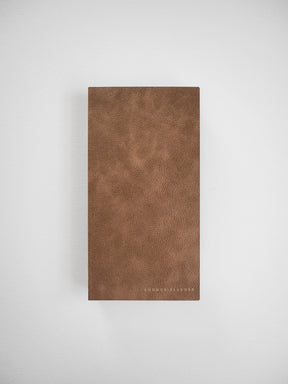 Deep tan, pebbled faux leather planner cover featuring a subtle grain texture and the "COMMON PLANNER" branding at the bottom.