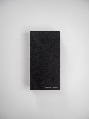 Minimalist black planner journal with a textured, simulated leather finish, prominently featuring gold metallic lettering that reads "COMMON PLANNER."