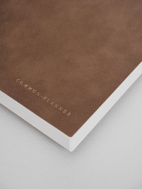 Minimalist A5 planner in rich brown tones, featuring debossed lettering for the "Common Planner" title.