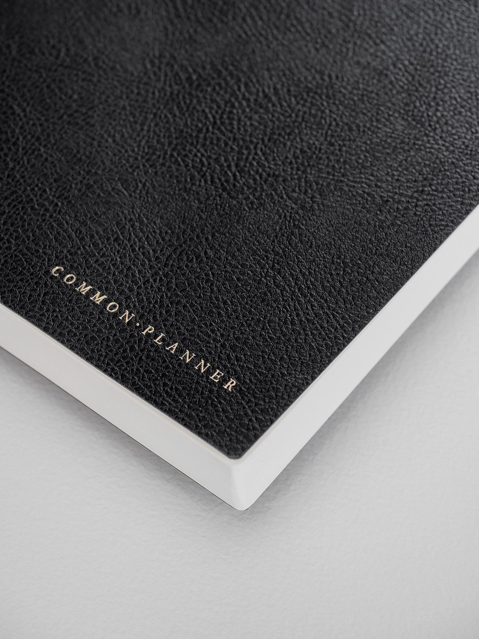 Elegant black textured planner cover featuring subtle graining and the metallic gold title "COMMON PLANNER."