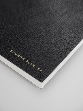Sleek, dark gray B6 vertical planner featuring debossed gold lettering that reads Common Planner, ready for tracking goals and schedules.
