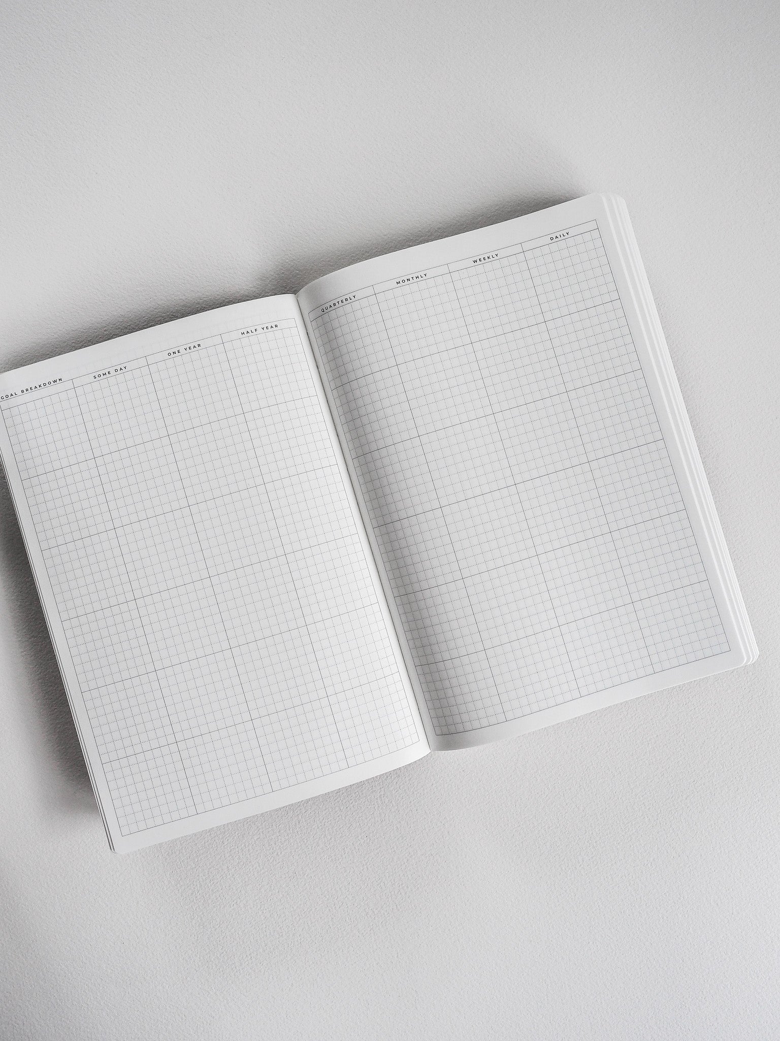Open A5 undated planner displaying clean, neutral grid paper optimized for detailed planning, featuring labeled sections for daily, weekly, and monthly organization.