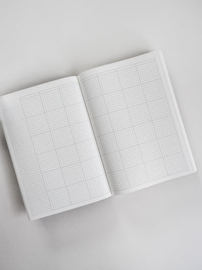 Open A5 undated common planner book displaying neat, light-colored graph paper, ideal for customizable note-taking and detailed planning grids.