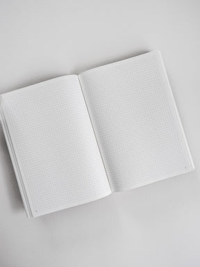 Open A5 spiral-bound planner showcasing clean, gridded graph paper perfect for detailed note-taking, budgeting, and comprehensive year-long planning.