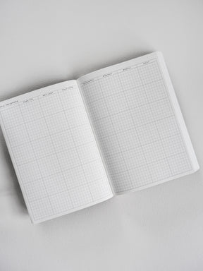 Grid-patterned undated planner showing structured sections for goal breakdowns, monthly tracking, and daily time management layouts.