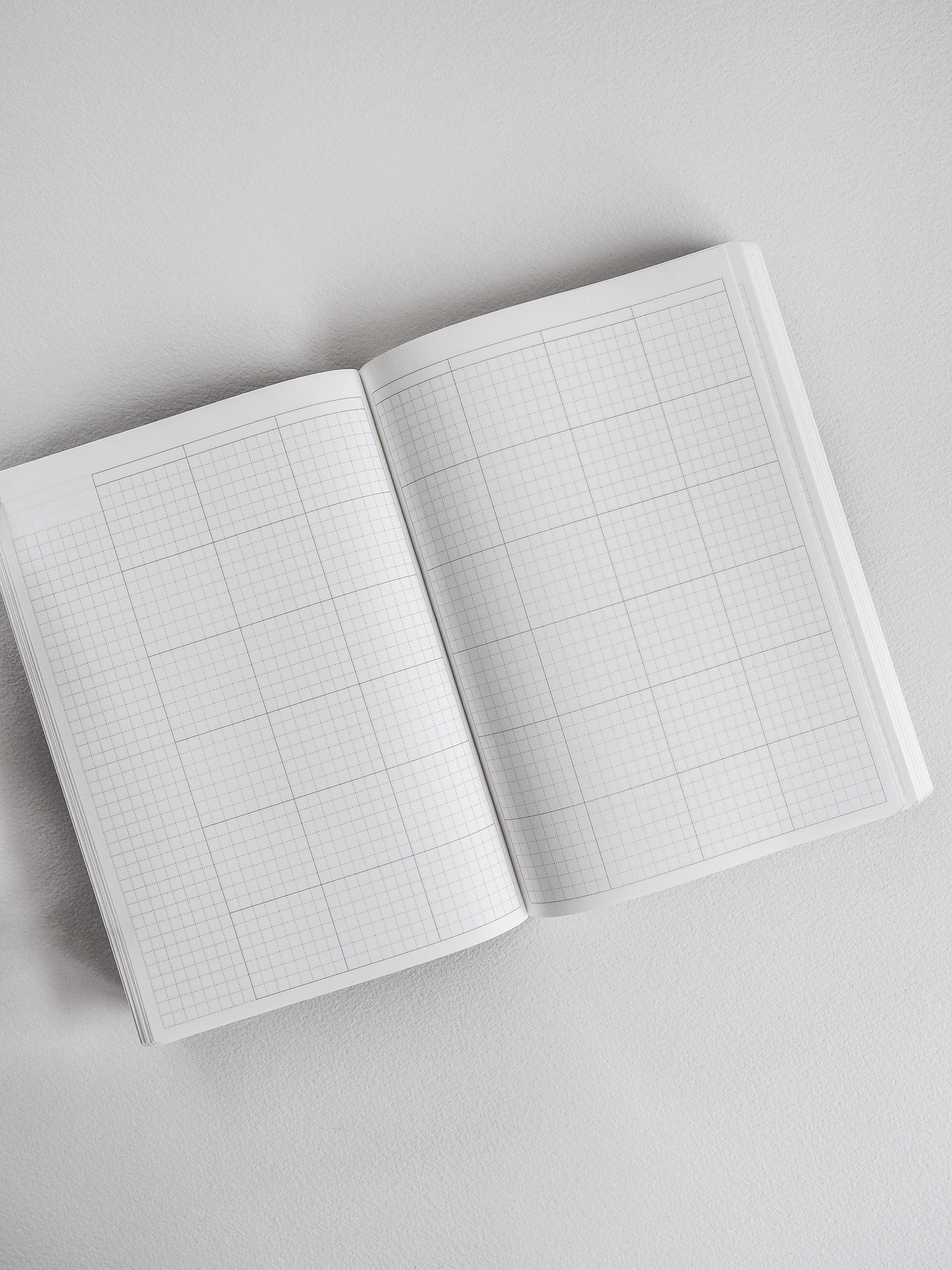 Open B6 planner book showing two pristine, white pages filled with delicate grid lines for structured, undated common journaling or note-taking.