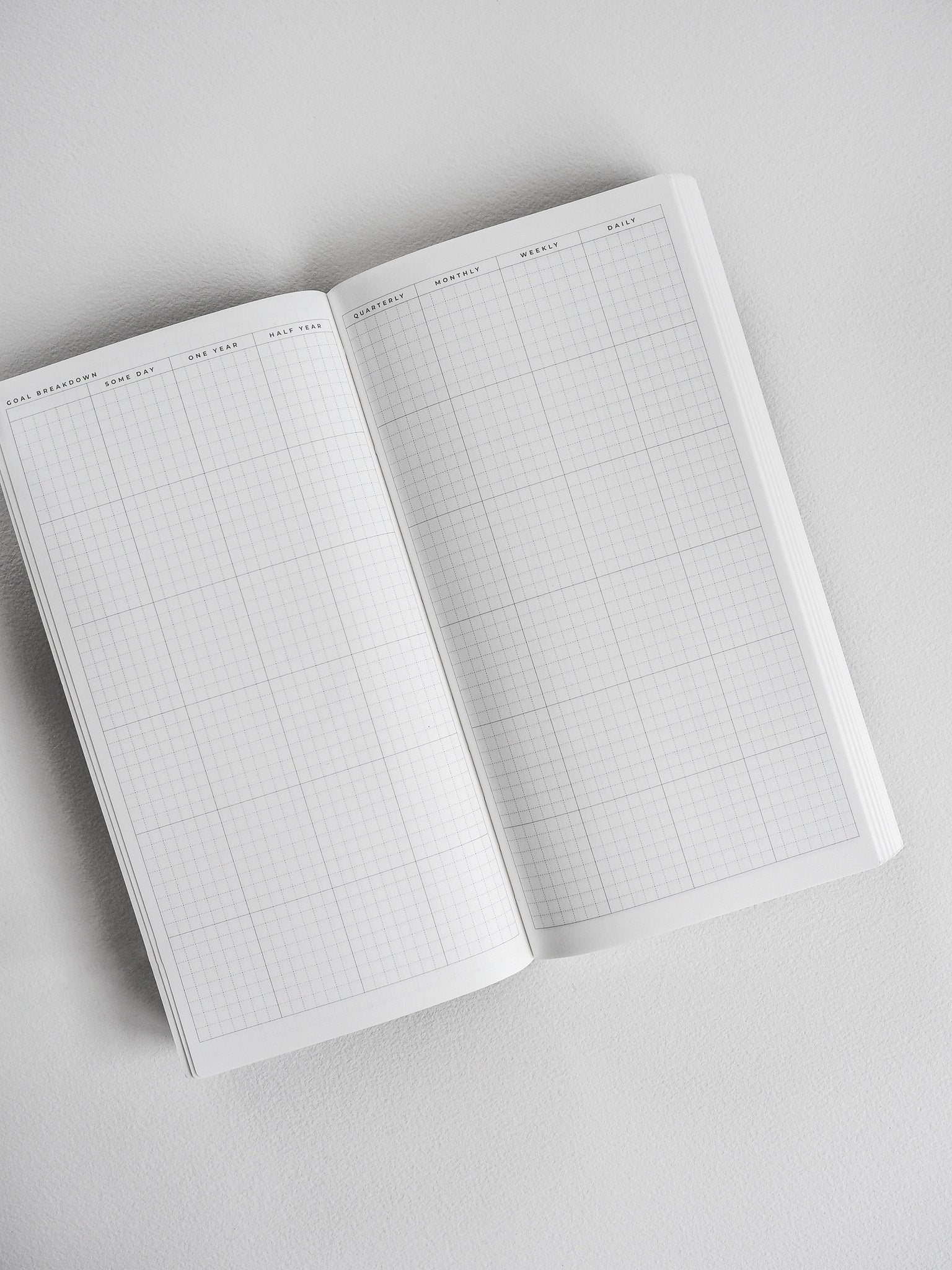 Open planner book revealing light gray graph paper grids designed for structured undated daily and weekly planning.