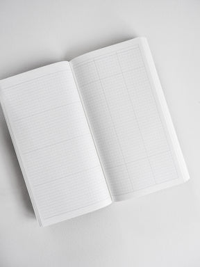 Open planner featuring precise light blue grid graph paper across two pages, designed for year-round versatile planning and note-taking.