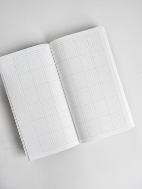 Open compact planner displaying a clean, white grid layout with fine gray lines, ideal for versatile note-taking or bullet journaling.