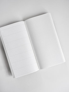 Open planner displaying crisp, comprehensive light-toned graph paper with precise grid lines for meticulous planning and writing.