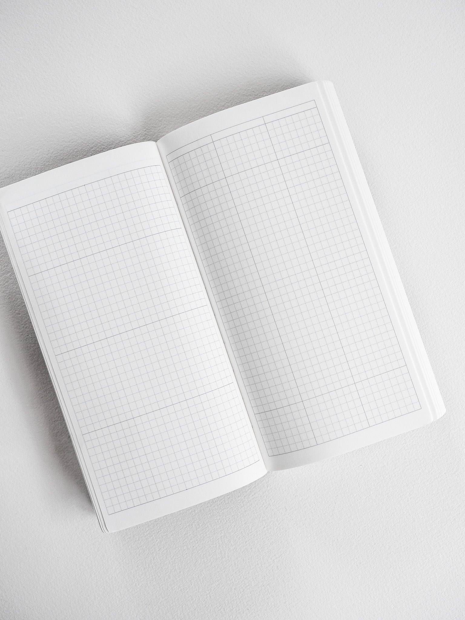 Open compact planner displaying pristine white graph paper grids, ideal for structured note-taking, planning, and detailed bullet journaling across a full year.