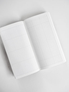 Open planner showcasing two white pages covered entirely in a precise gridded graph pattern, ideal for structured planning and note-taking.