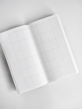 Open white planner featuring visible graph paper grids across both pages, perfect for undated, organized note-taking and scheduling.