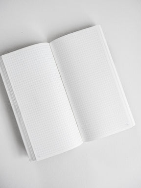 Open white undated planner displaying crisp graph paper grids across both pages for comprehensive yearly scheduling and detailed note-taking.